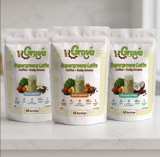 Three stand-up pouches of Grava Supergreens Latte coffee with daily greens are arranged on a white marble surface against a light gray background. Flavours featured are salted caramel
